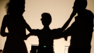 The large shadows of a woman from the audience turning the woman and man's head so they look at each other