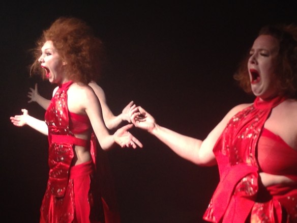 Three women in red arms raised in similar pose - screaming